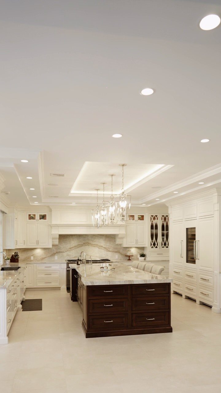 Dark brown wood kitchen island with white marble top in a white kitchen