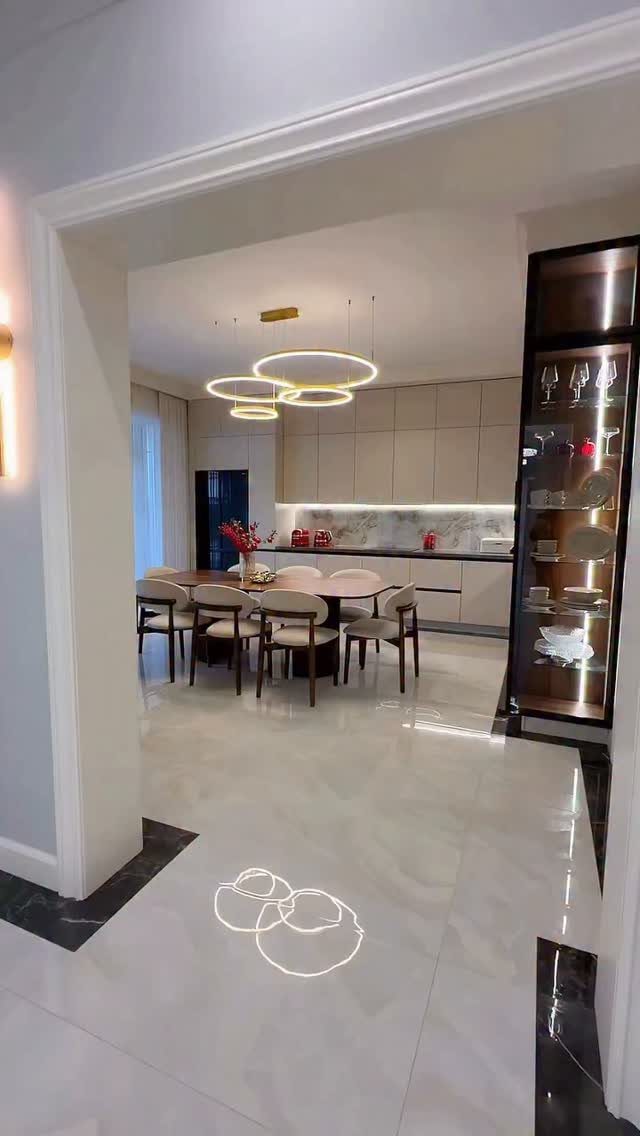 Three circular ring pendant lights hanging over a wooden kitchen dining table