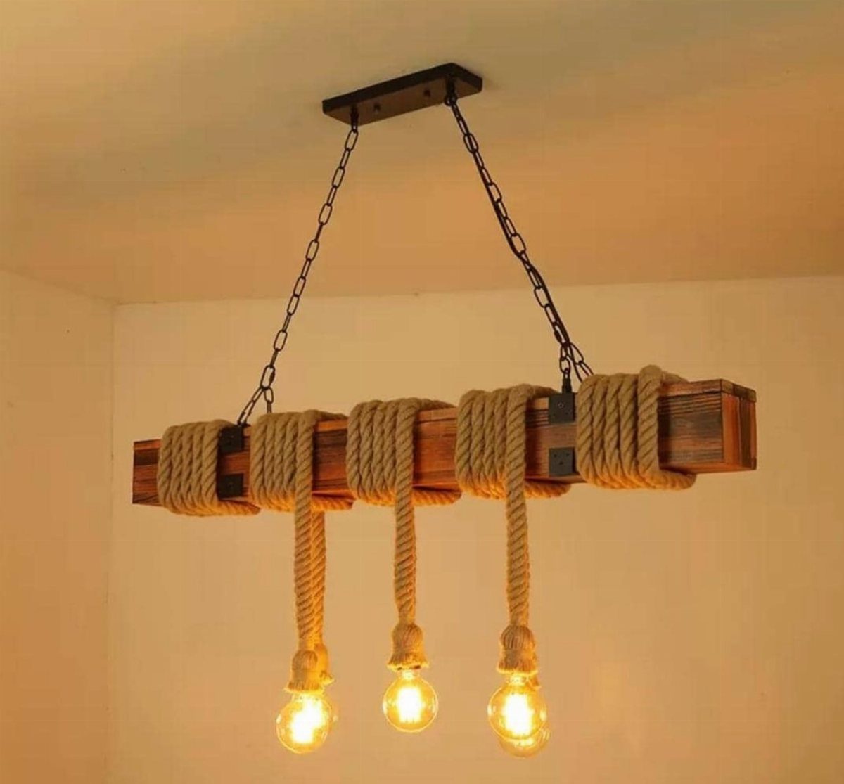 Rustic wooden beam light fixture with three glowing exposed bulbs hanging from ropes.