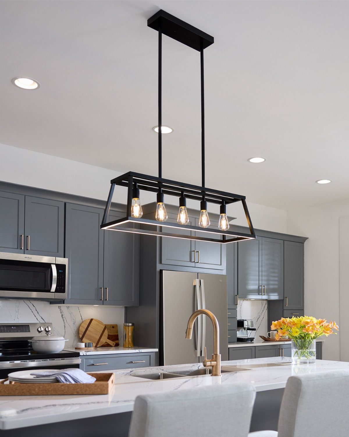Matte black linear light fixture with exposed bulbs over a white kitchen island