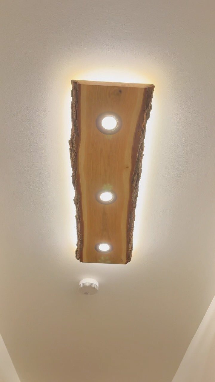 Wooden beam light fixture with three recessed bulbs mounted on a white ceiling