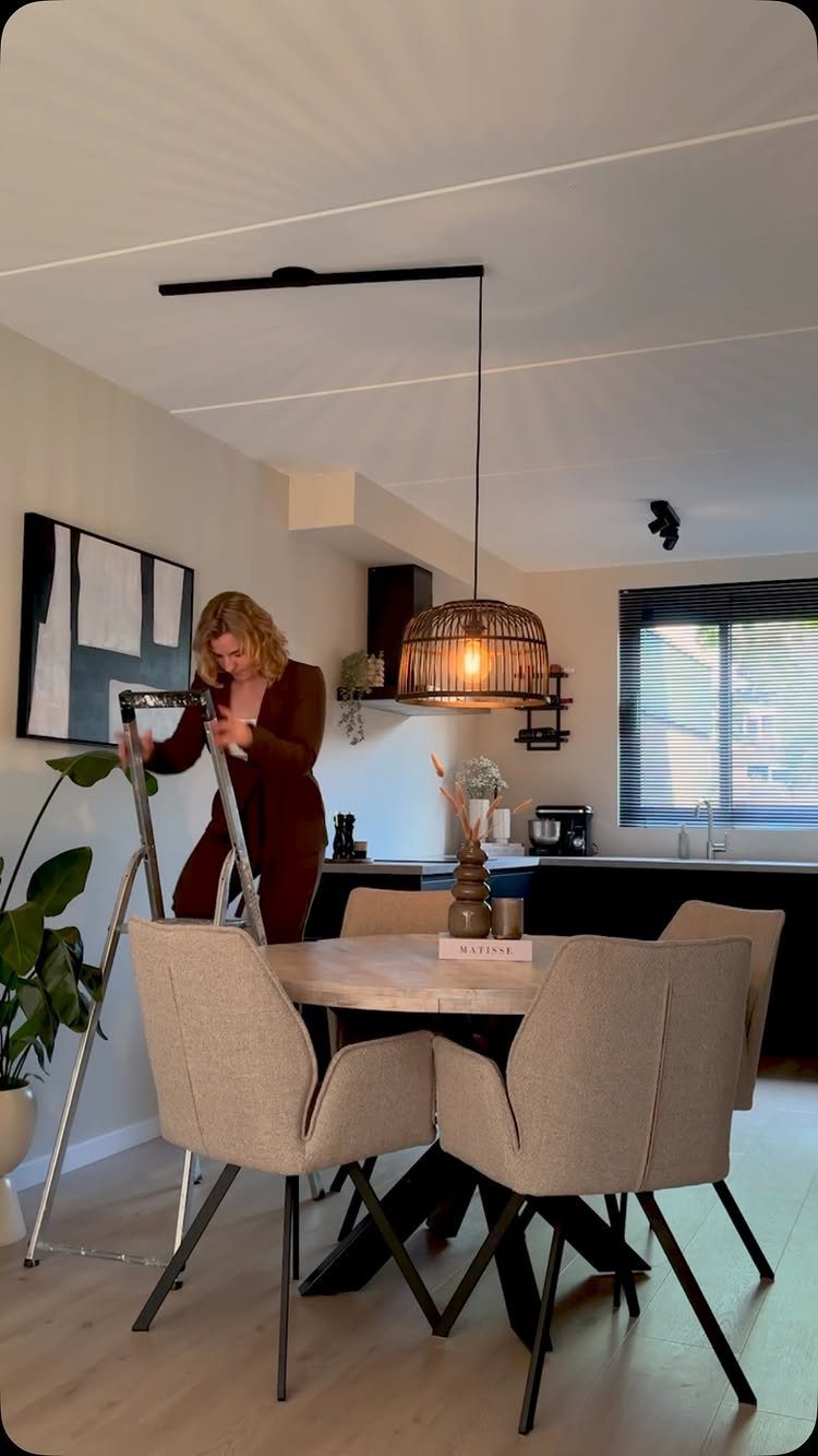 Woven wicker pendant light hanging over a round wooden kitchen dining table.