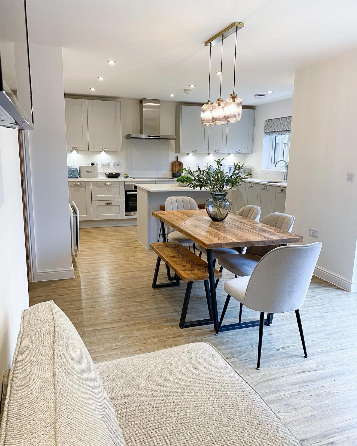 Open concept living area with a sofa, wooden dining set, and white kitchen.