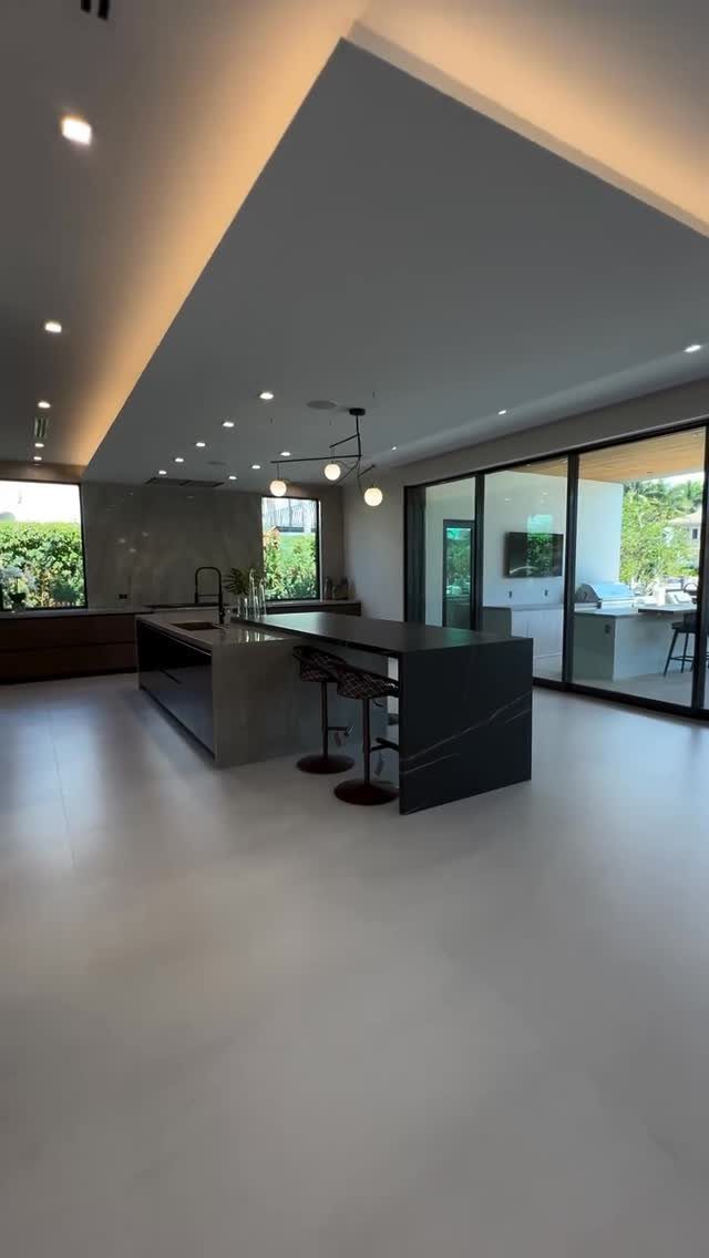 Dark grey kitchen island with bar stools in a bright open concept room