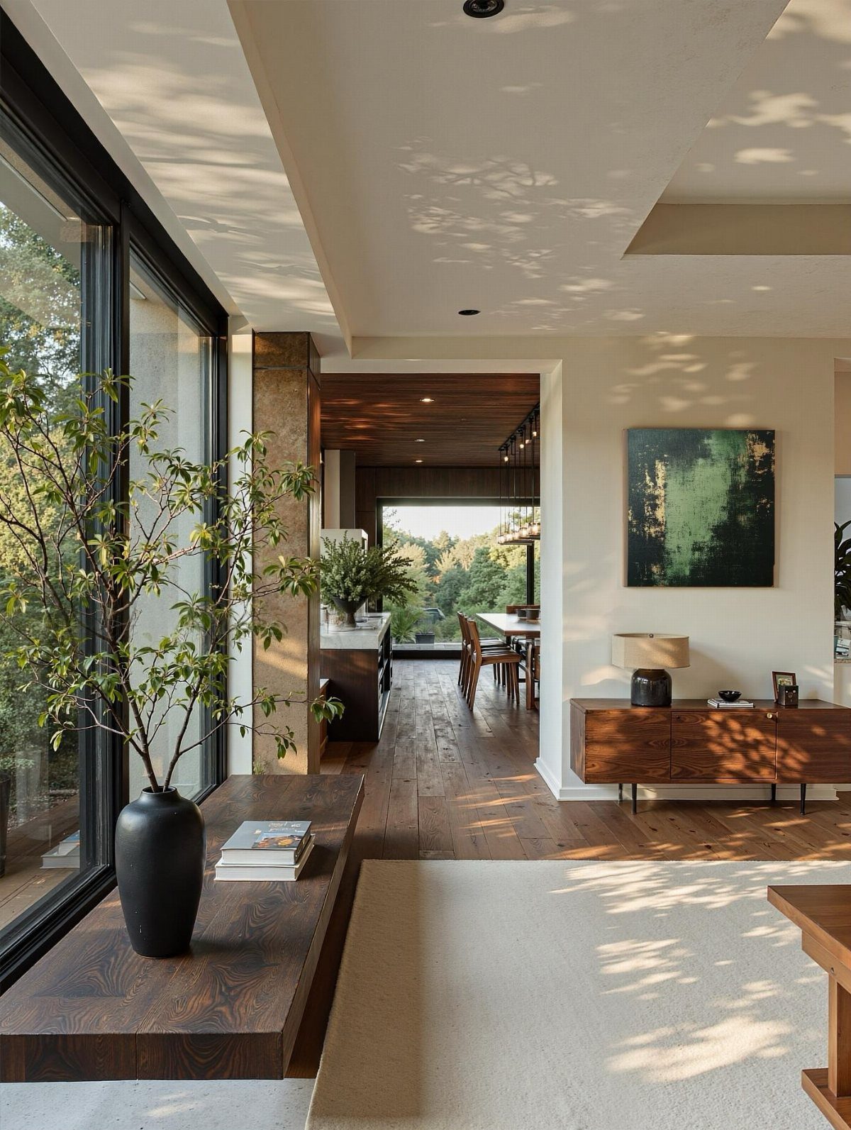 Modern open-concept interior with wood ceilings, stone pillars, and dark wood furniture.