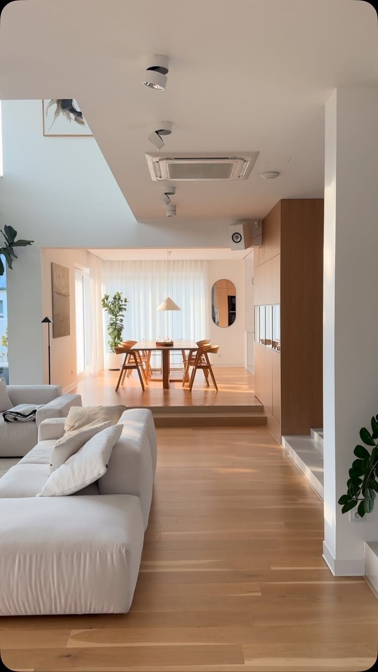 White sofa in a modern open-concept living area with a raised dining platform.