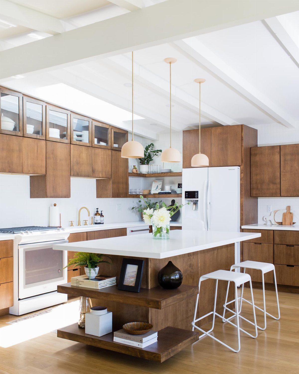 Flat-front wood cabinets in a bright mid-century modern kitchen with a white island.