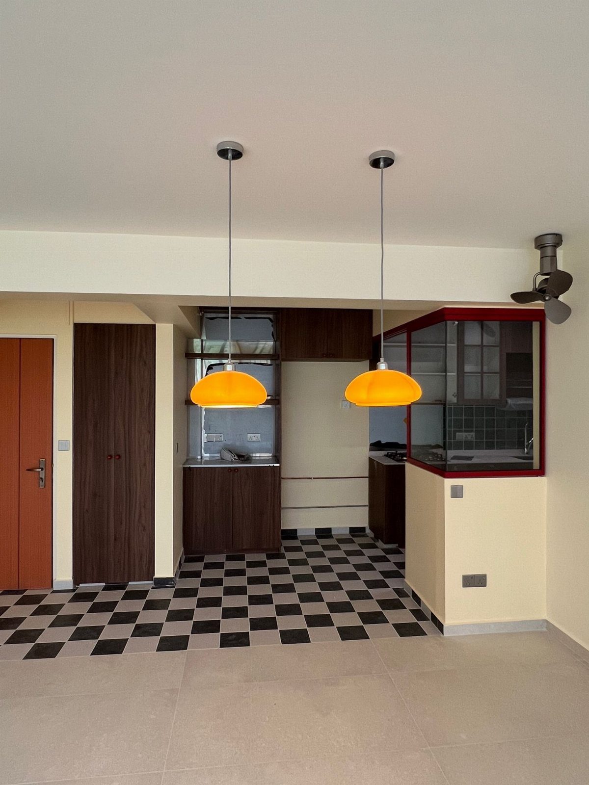 Kitchen with black and white checkered flooring and yellow dome pendant lights.