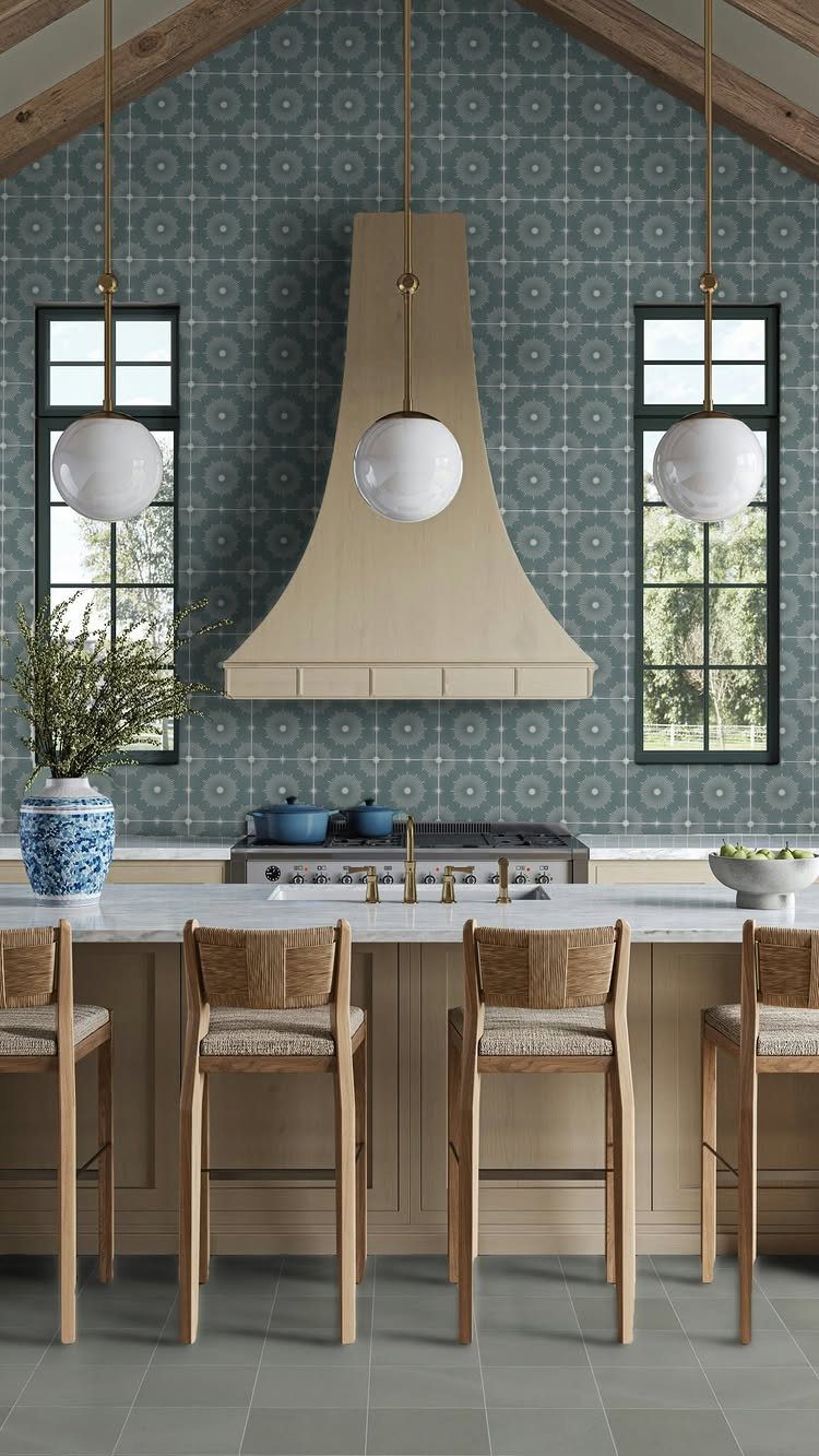 Blue geometric tile backsplash in a kitchen with wooden stools and globe lights.