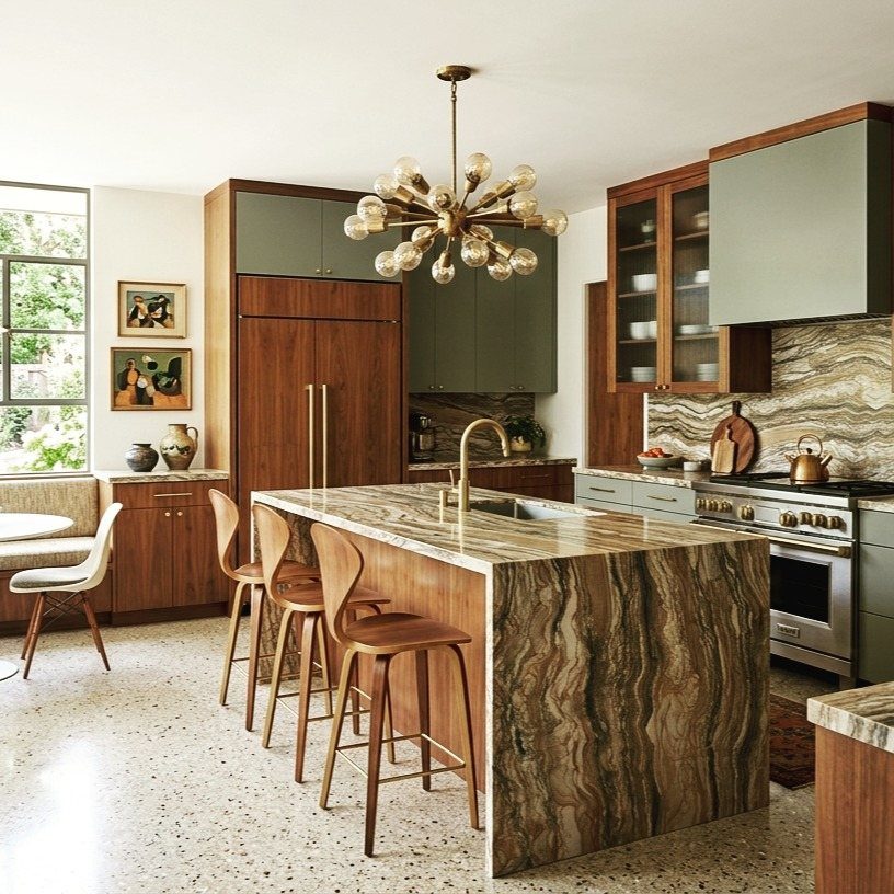 Gold sputnik chandelier hanging over a marble kitchen island with wooden stools.