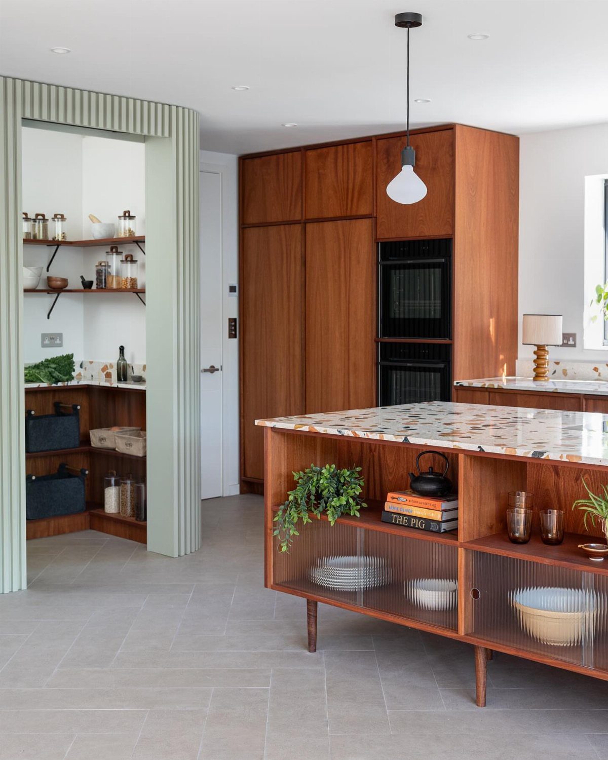 Kitchen island with a speckled terrazzo countertop and warm wood cabinetry.