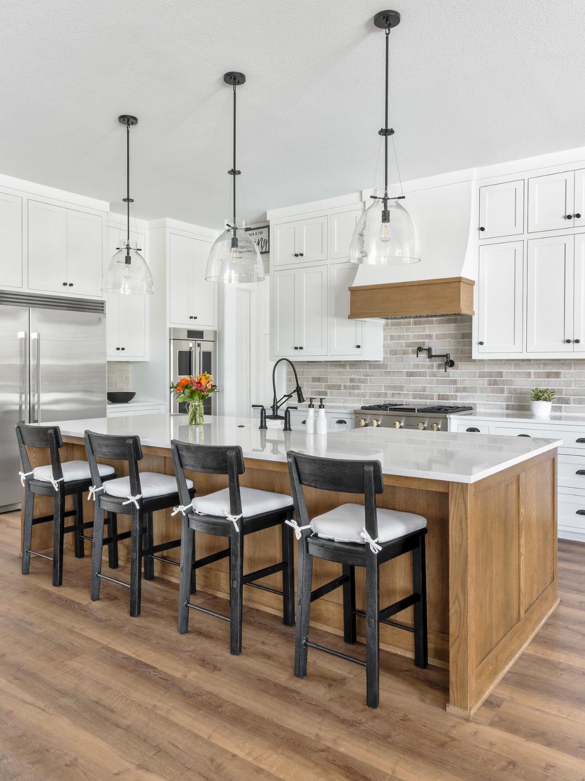 Modern farmhouse kitchen with wood island, white cabinets, and glass pendant lights.