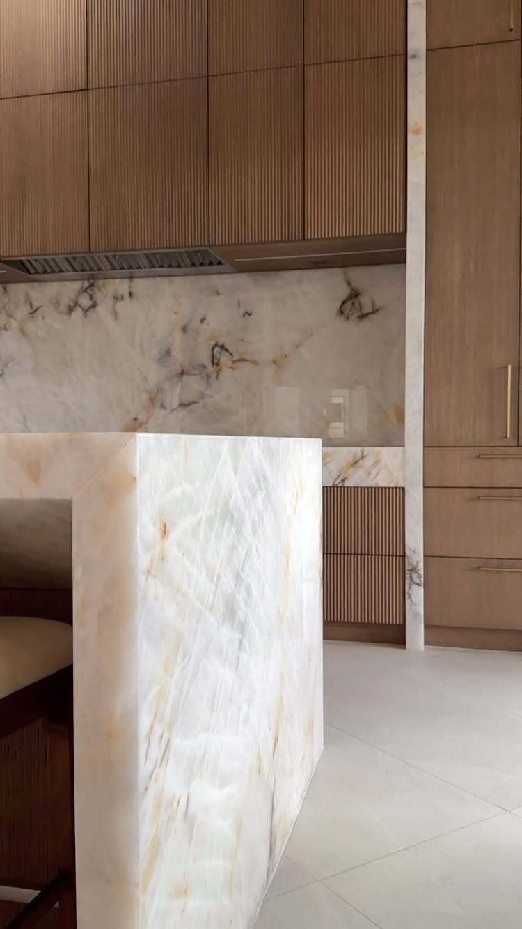 Light brown wooden cabinets with ribbed texture and white marble countertops in kitchen