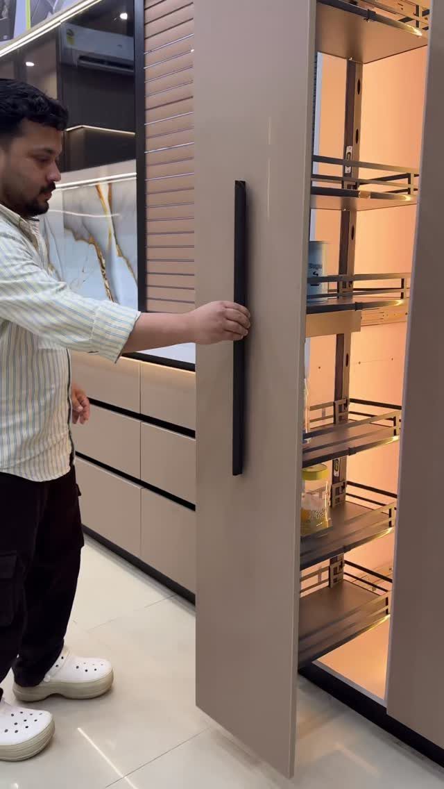Man opening a beige modern kitchen cabinet with a pull-out pantry organizer.
