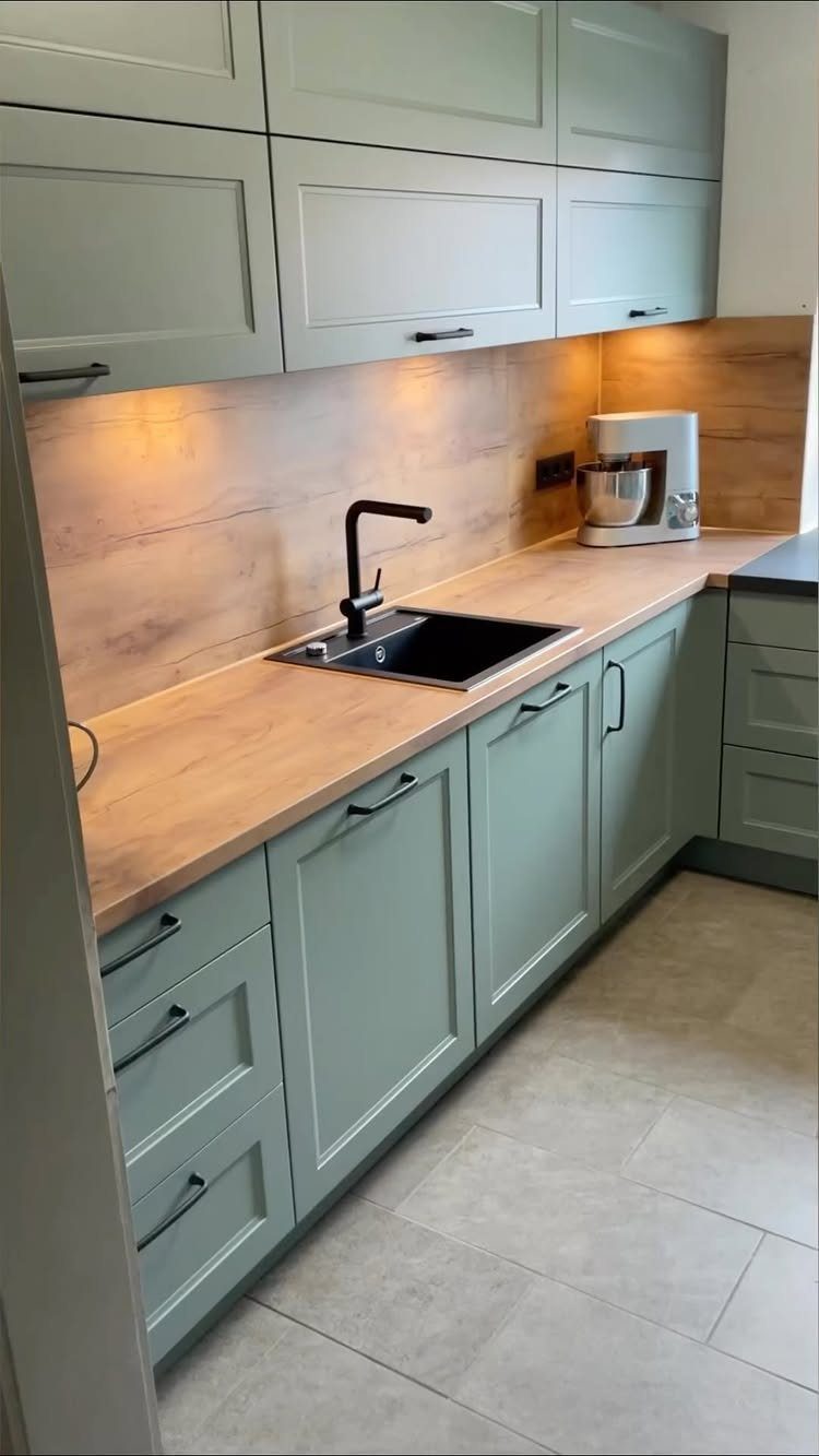 Matte moss green shaker cabinets with light wood countertops and matching wood backsplash.