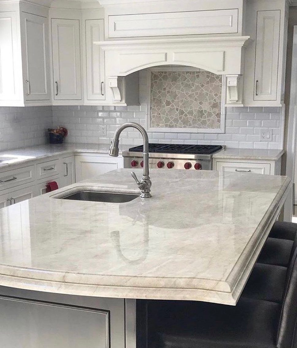 White kitchen with marble island and grey subway tile backsplash with mosaic insert