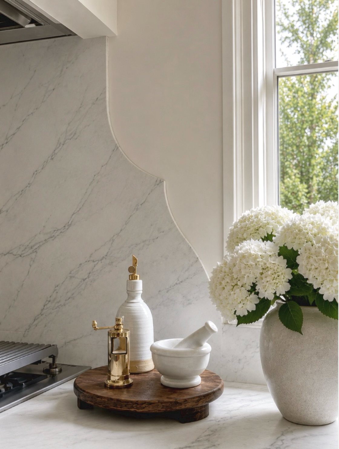 White marble slab backsplash extending from counter to cabinets in a bright kitchen.