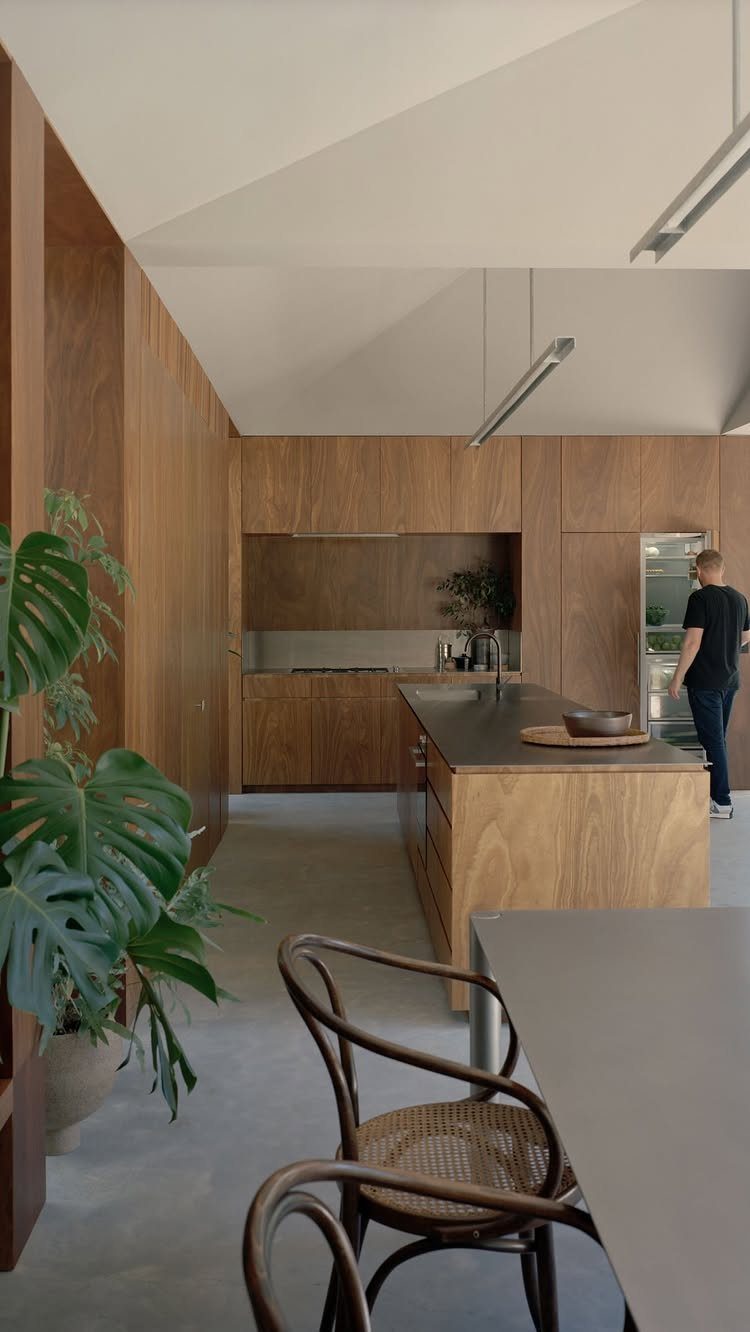 Dark brown natural wood kitchen cabinets and island in a modern minimalist home.