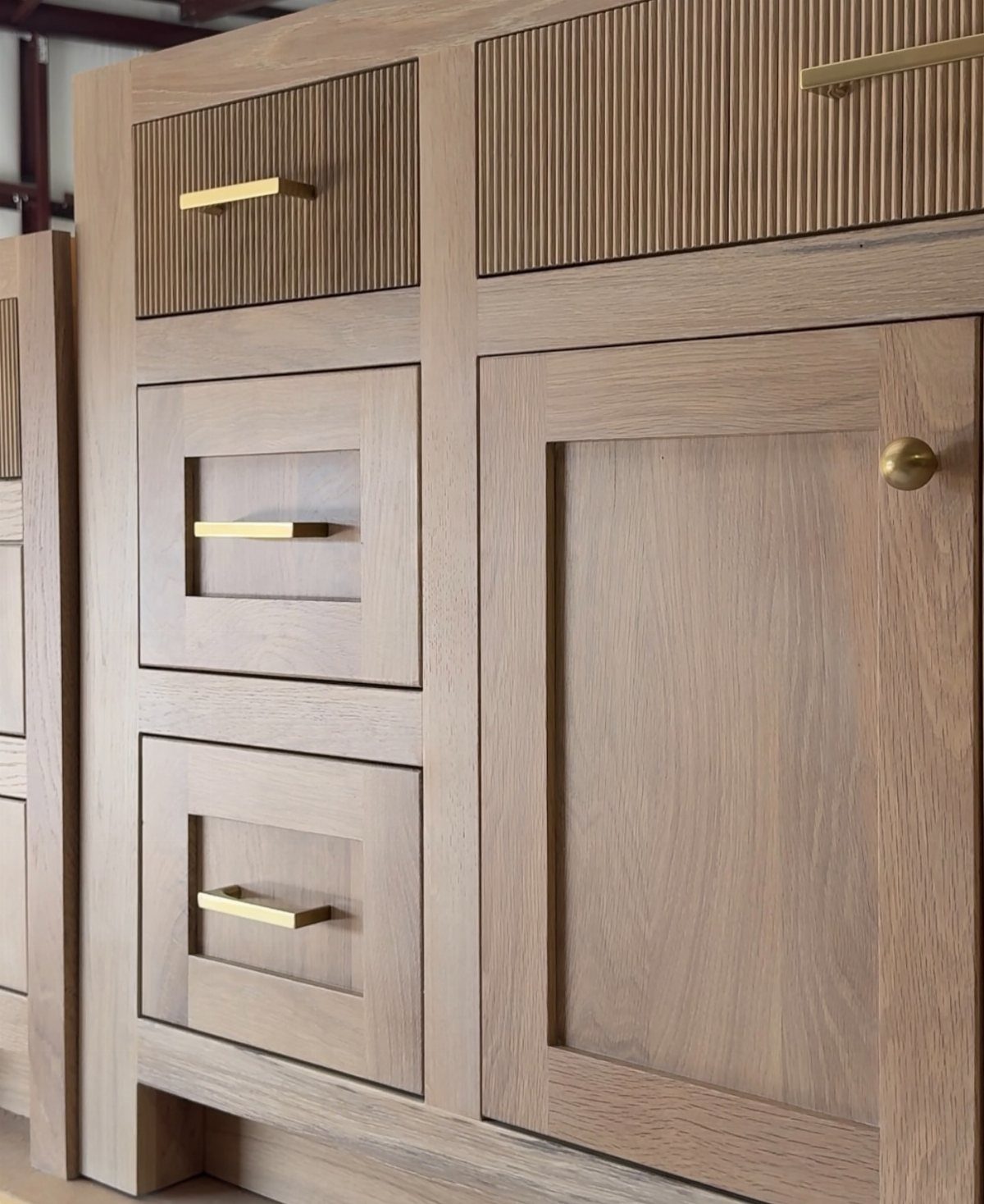 Light wood kitchen cabinets with ribbed textures and gold hardware in close-up view.