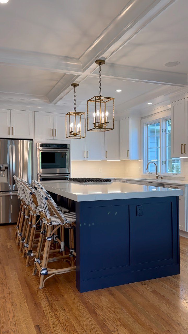Navy blue kitchen island with white countertop and gold lantern pendant lights.