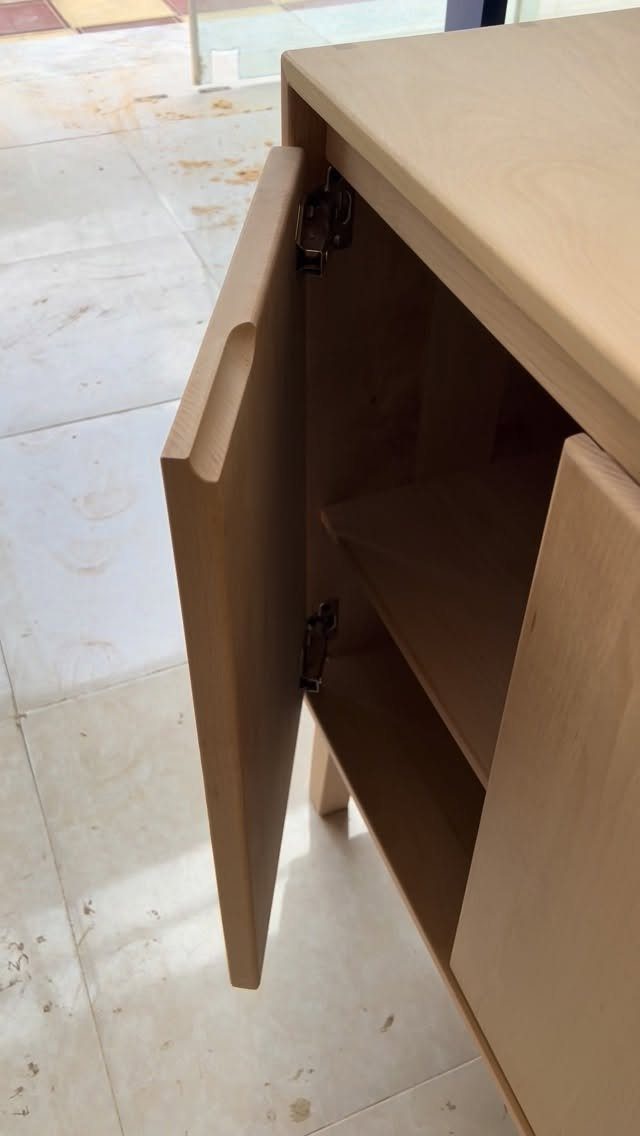 Light oak wooden cabinet with an open door and interior shelving on tiled floor