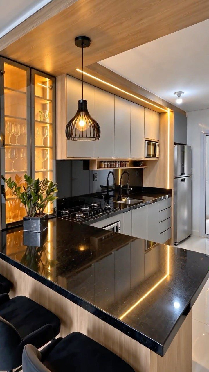 Modern kitchen with light oak cabinets, black granite countertops, and warm LED lighting.