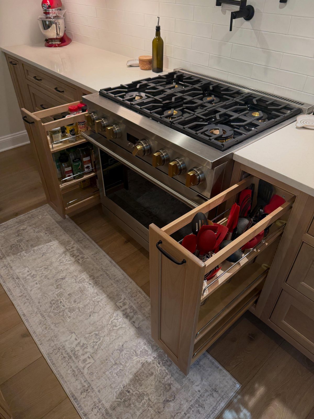 Light oak kitchen cabinets with pull-out storage racks next to a stainless steel range.