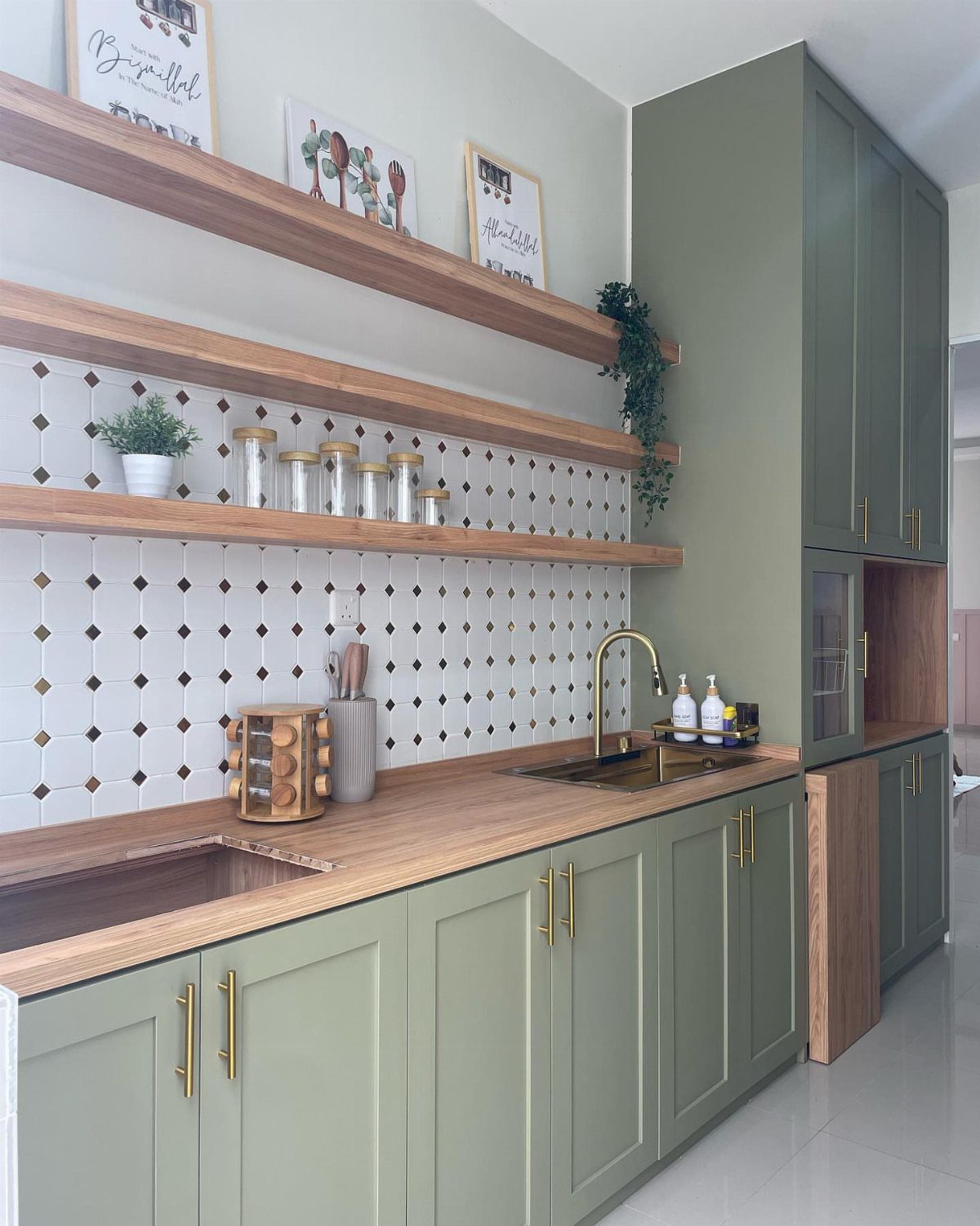 Olive green kitchen cabinets featuring sleek gold hardware and a matching gold faucet.