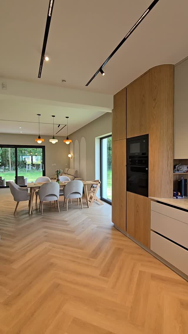 Modern open plan kitchen and dining area with light wood and neutral tones.