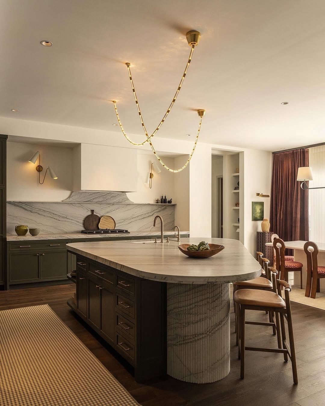 Modern open kitchen and living room with a large marble island and wooden stools.