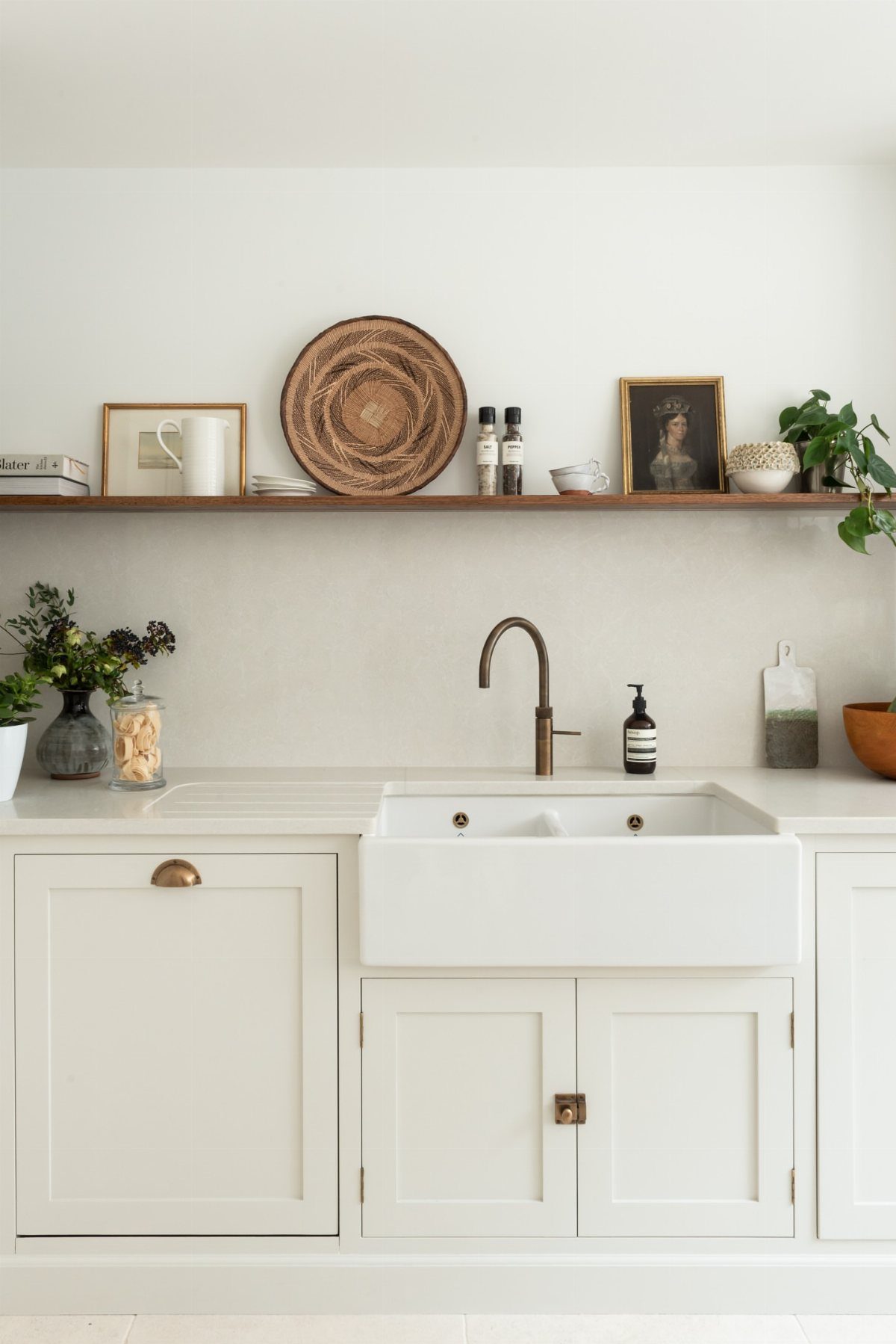 Wooden floating shelf installed above a white farmhouse sink in a bright kitchen.