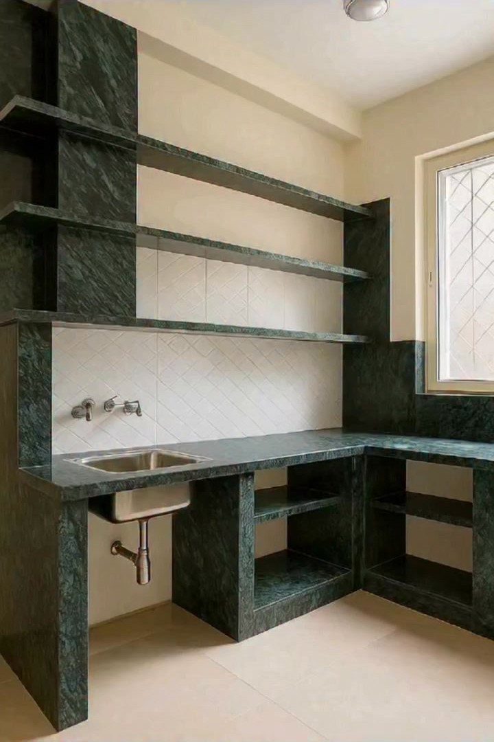 Dark green marble open shelving and countertops in a modern kitchen with sink.