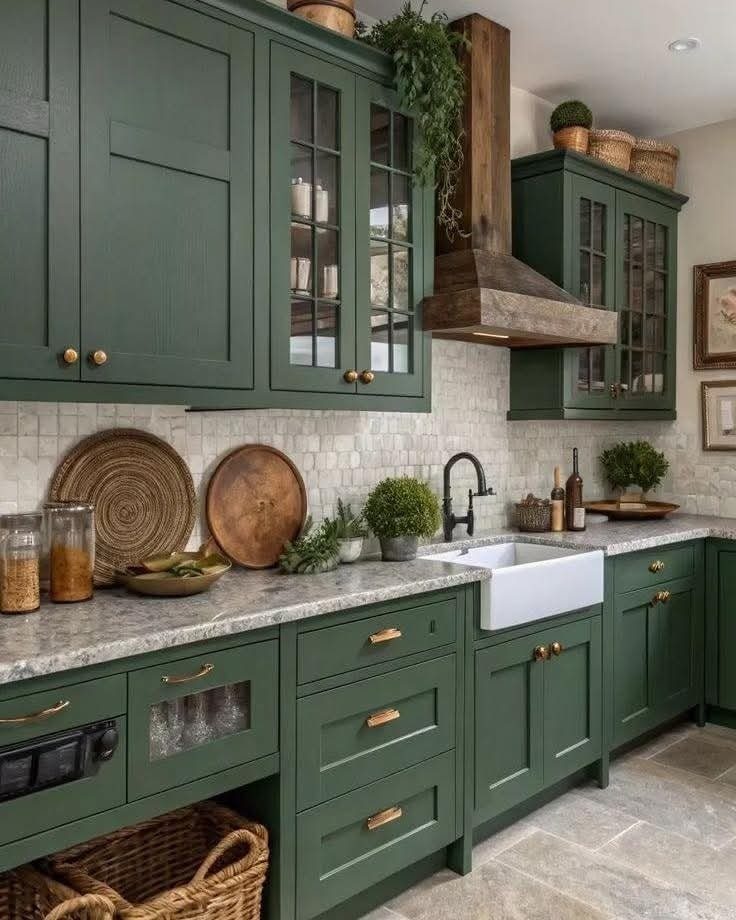 Olive green kitchen cabinets with gold handles and white marble countertops.