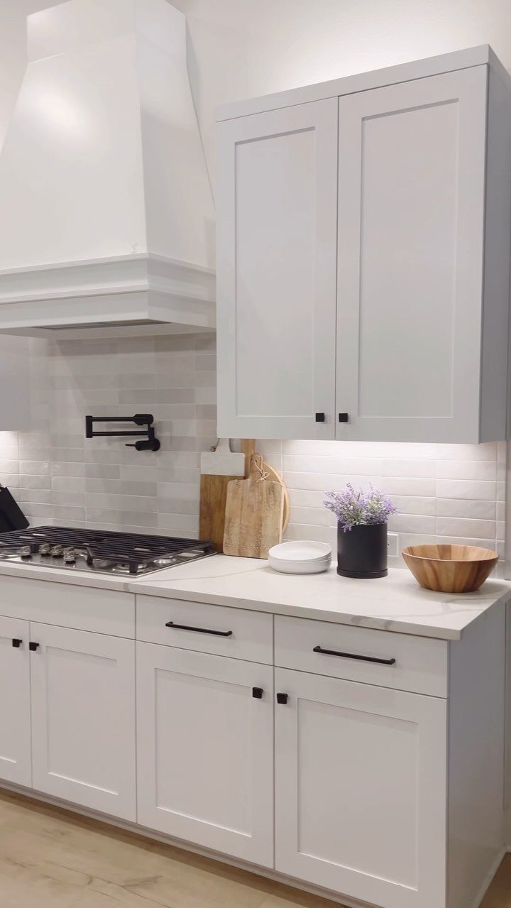 White shaker-style kitchen cabinetry with white countertops and a matching range hood.