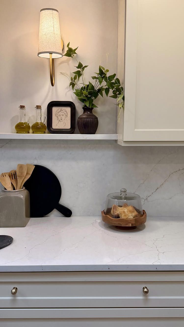 Creamy white kitchen cabinets with gold hardware and a white marble countertop.