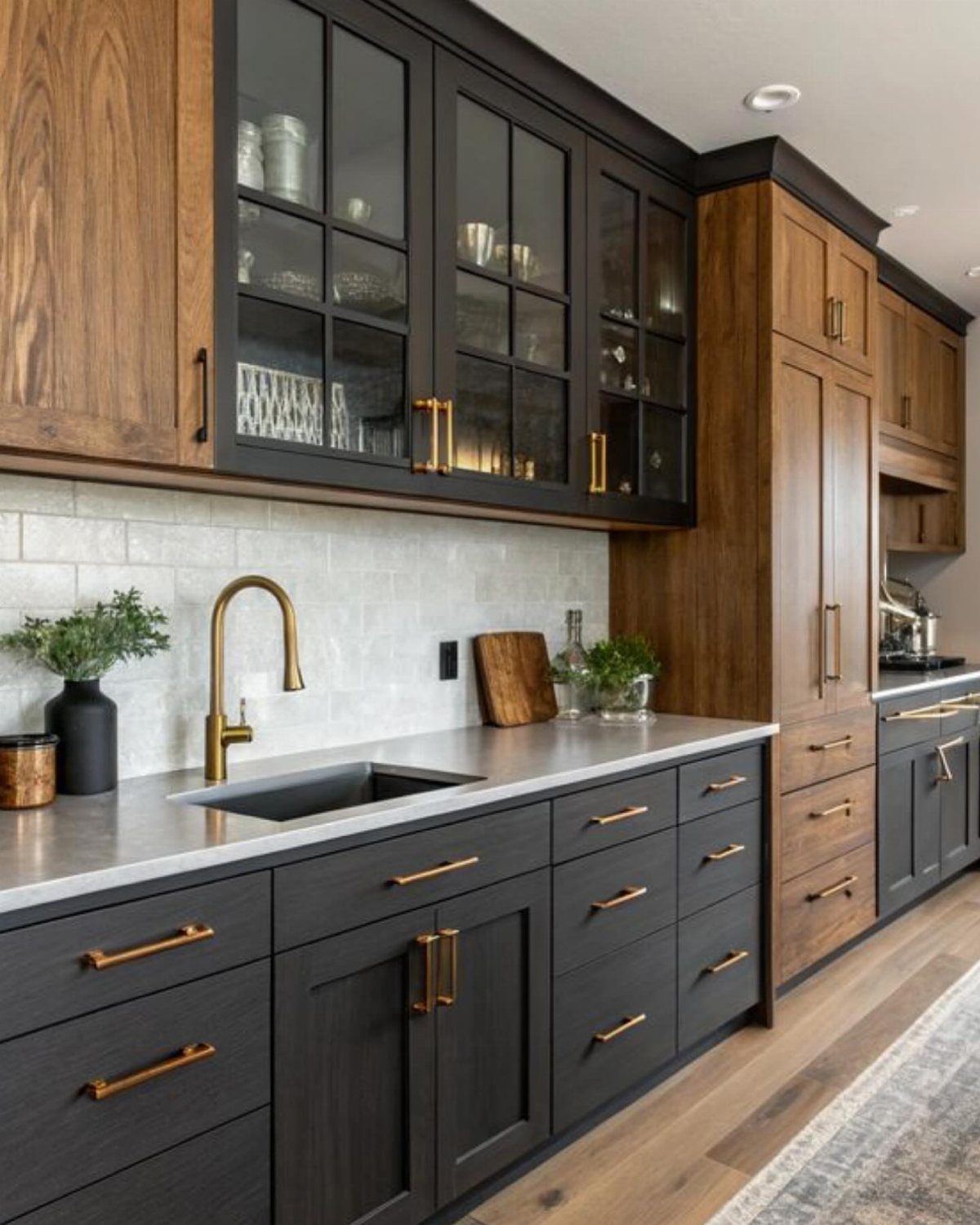 Charcoal grey kitchen cabinets with gold hardware and contrasting warm wood cabinetry.