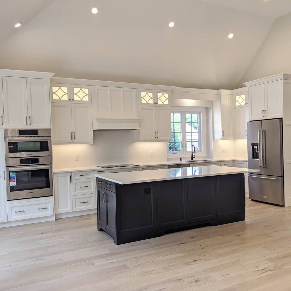 White kitchen cabinets with a contrasting dark navy blue center island and stainless appliances.