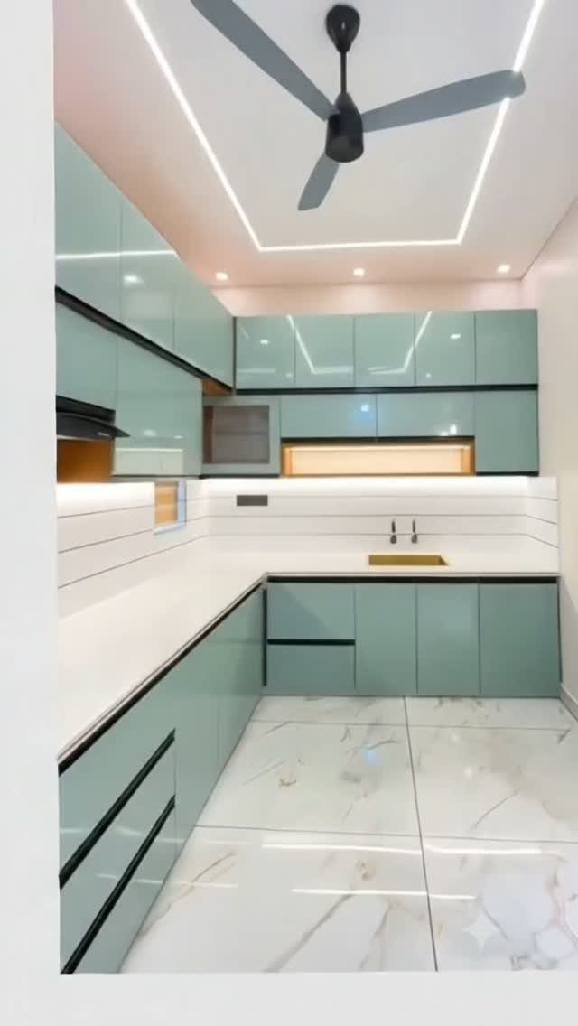 Pale blue-green glossy kitchen cabinets with white countertops and marble flooring.
