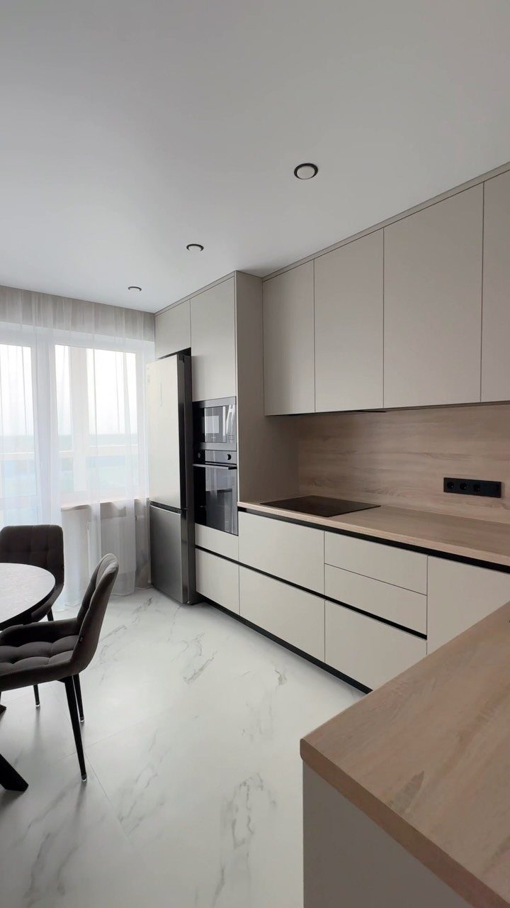 Greige kitchen cabinets with light wood countertops and white marble flooring in modern interior