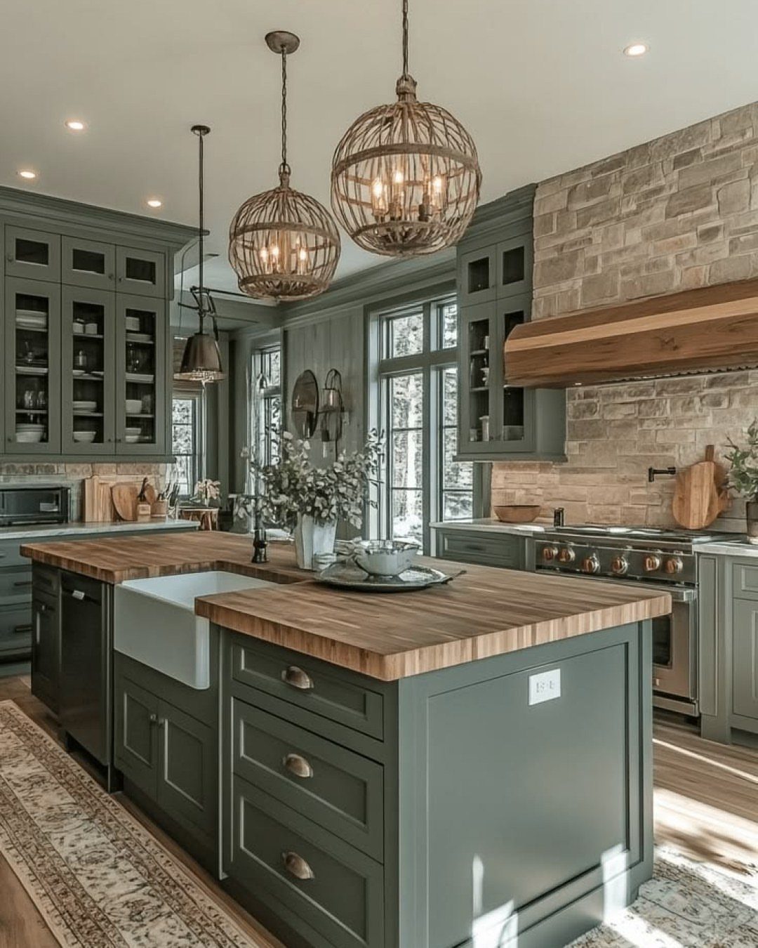 Sage green farmhouse kitchen with wooden island, white apron sink, and stone walls.
