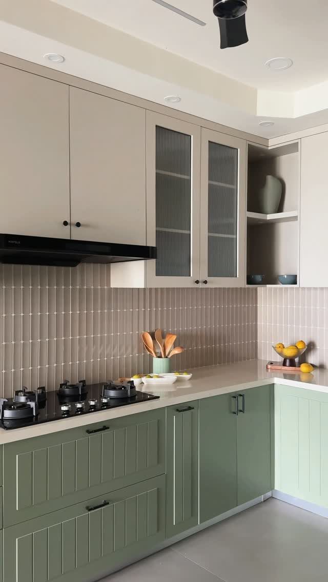 Sage green lower cabinets and cream upper cabinets in a modern kitchen setting.