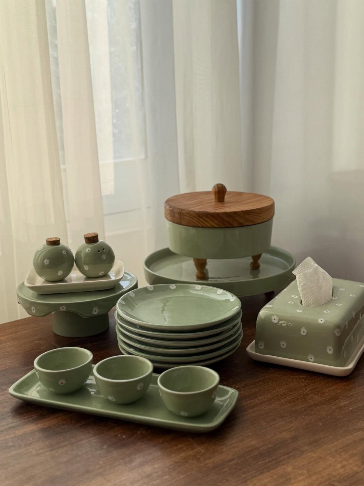 Sage green ceramic dishware set with white polka dots on a wooden table