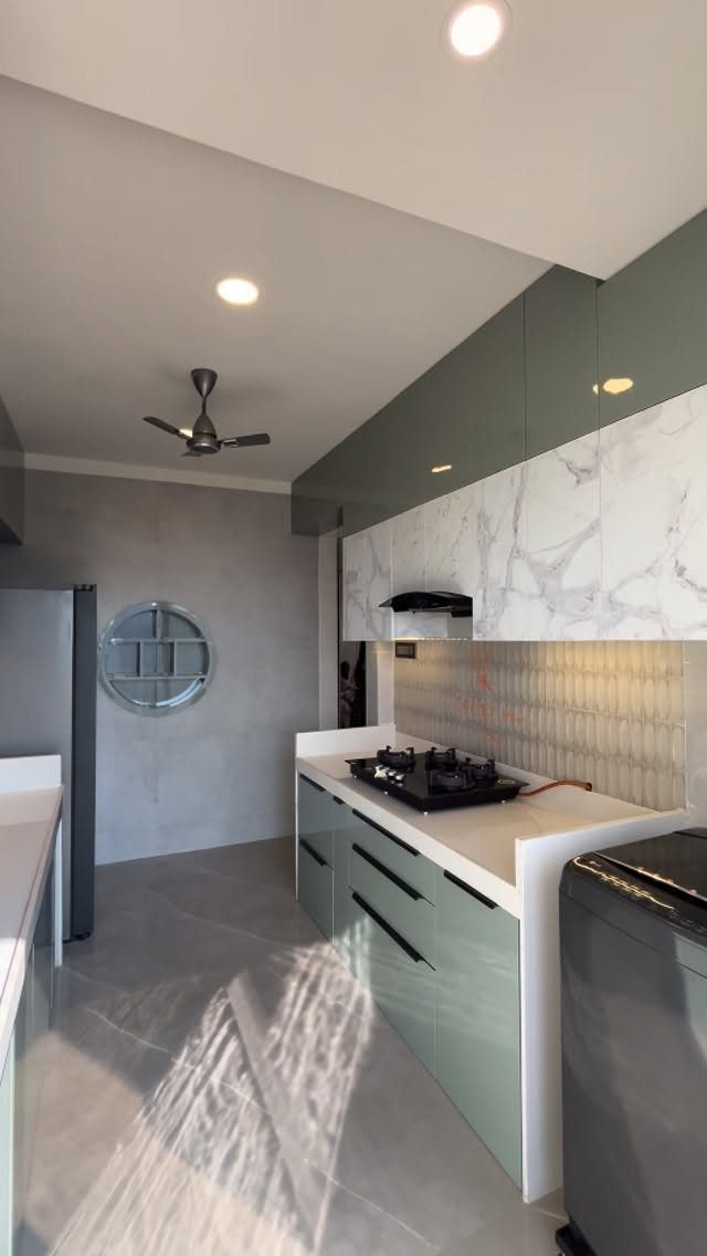 Sage green kitchen cabinets with a white marble backsplash and white countertops.