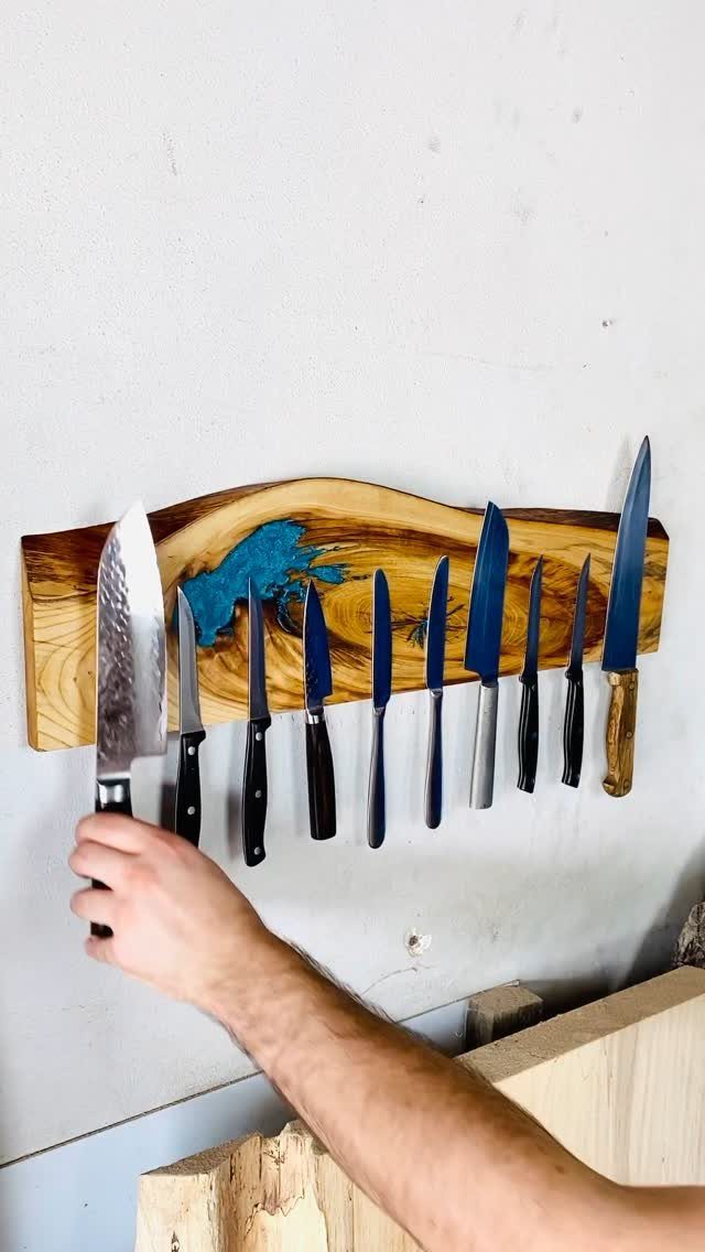 Magnetic wooden knife strip on a white wall holding various kitchen knives.