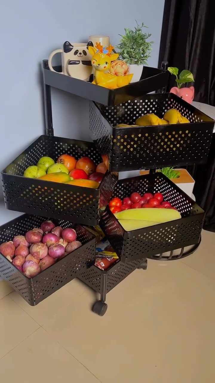 Black metal rolling cart with perforated baskets filled with fresh produce and decor.