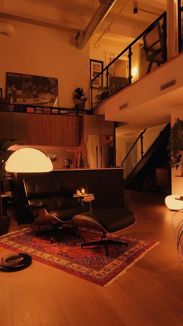 Modern open-concept studio with a leather lounge chair and small wood kitchen.