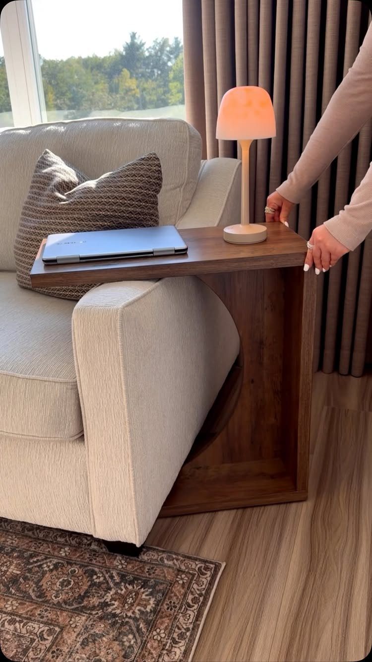 Light fabric sofa with a wooden C-table holding a laptop and lamp.
