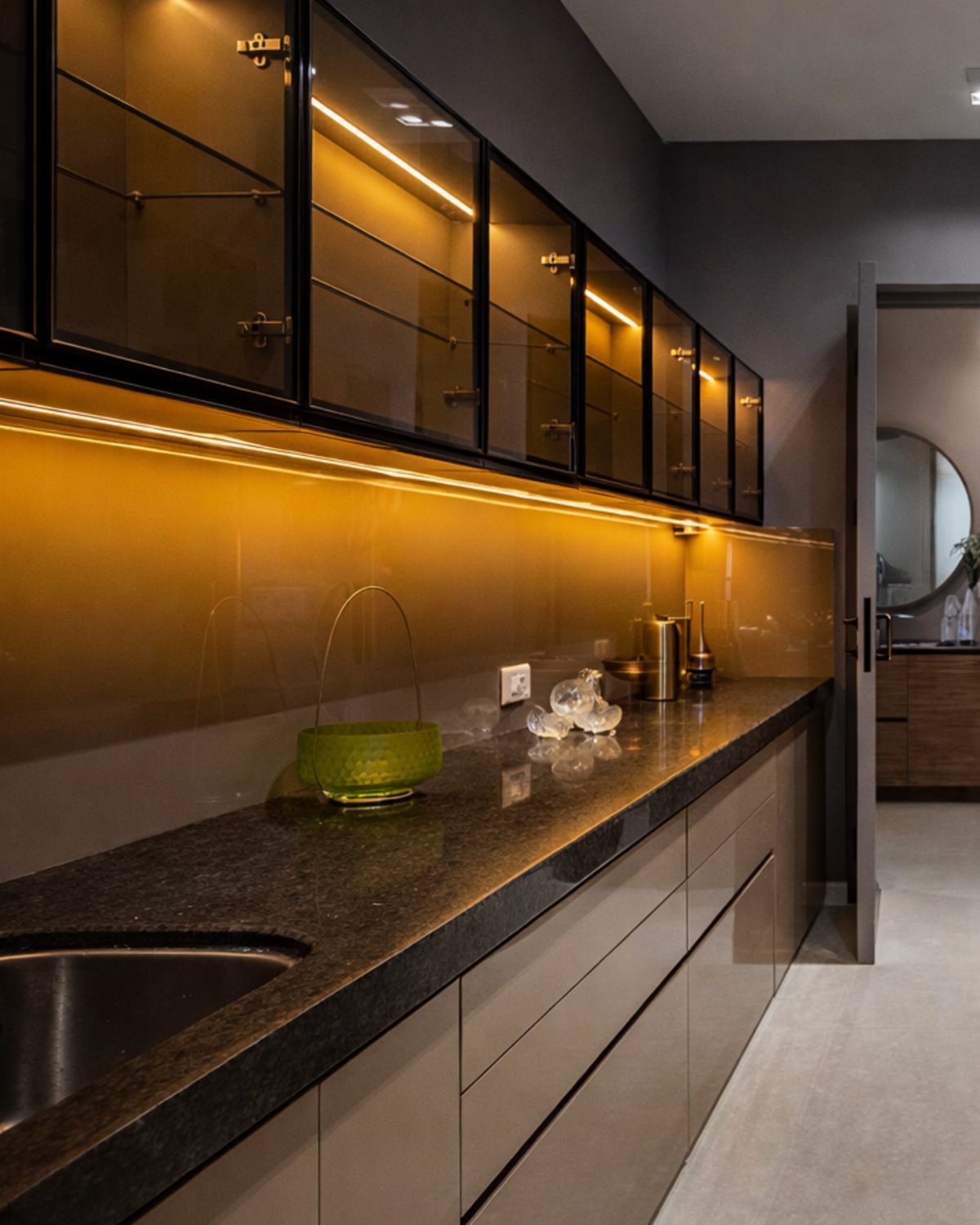 Glass-front upper cabinets with interior lighting above a dark stone kitchen countertop.
