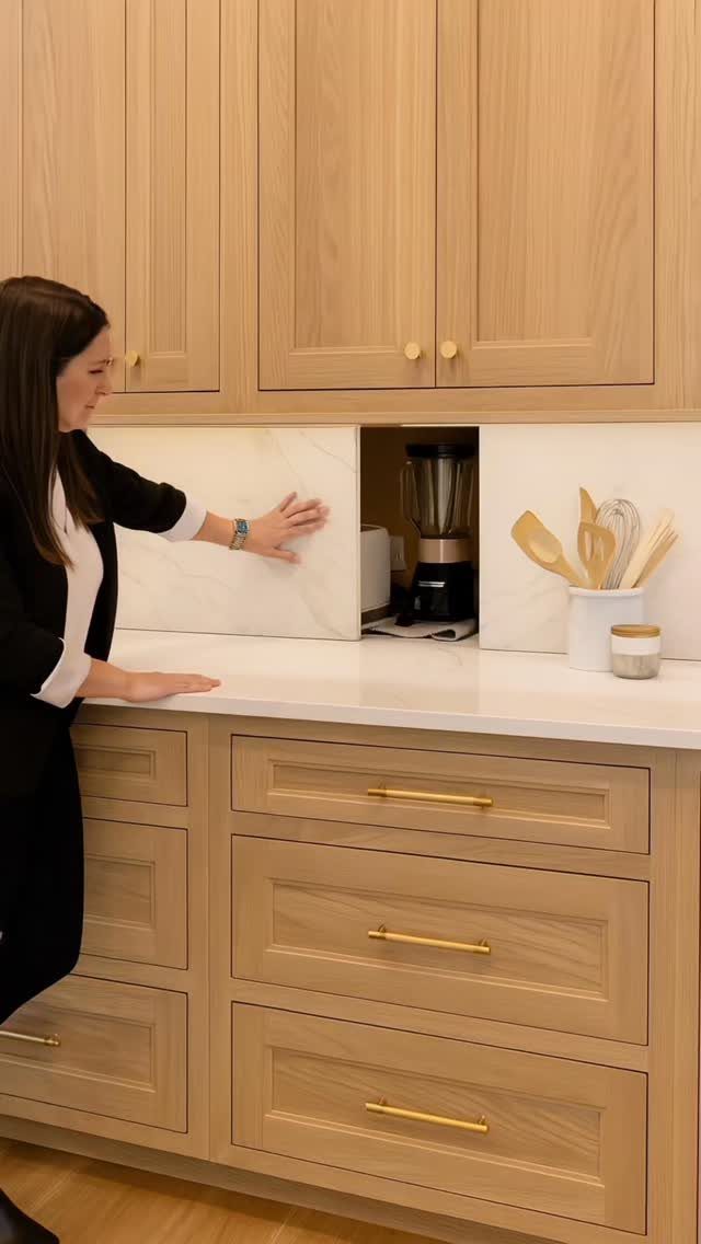 Woman sliding a hidden panel to reveal a blender in a wood kitchen.