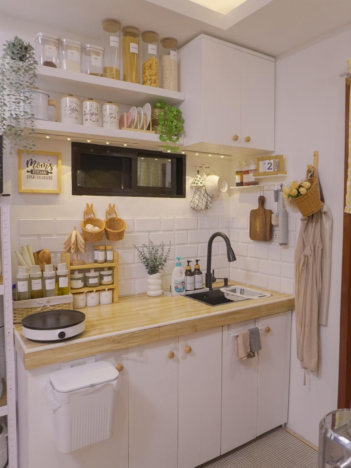 Small one-wall kitchen with white cabinets, wood countertops, and open shelving jars.